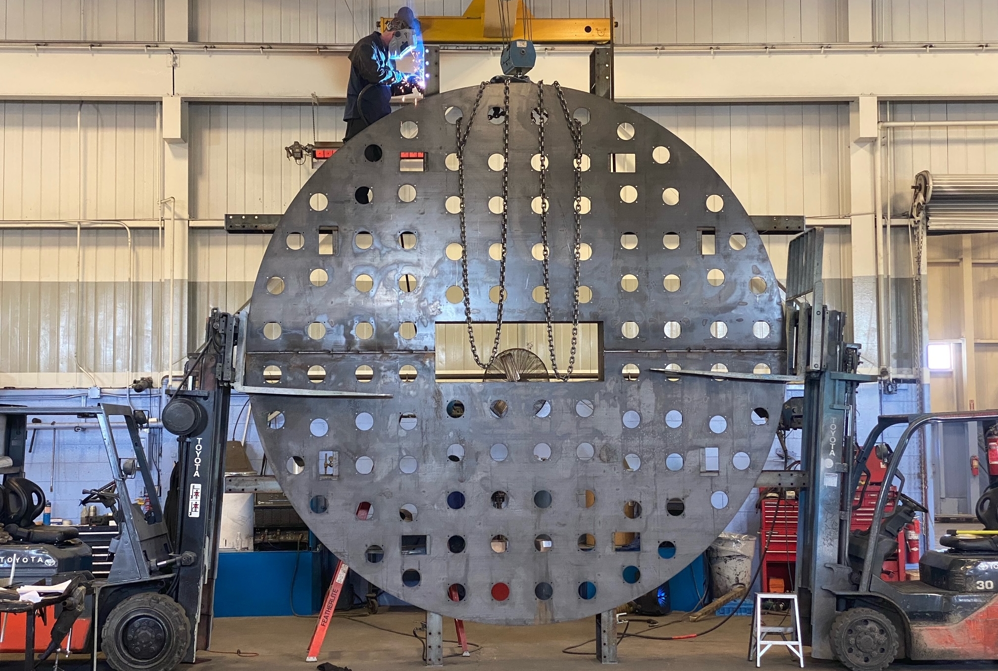 Large circular disk being worked on by a welder.